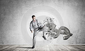 Determined banker man in empty concrete room breaking dollar fig