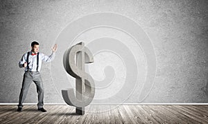 Determined banker man in empty concrete room breaking dollar figure