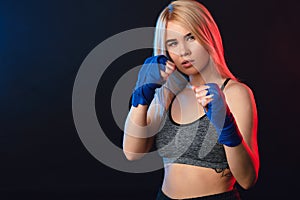 Determined blonde female boxer in blue handwraps gets prepared for fight