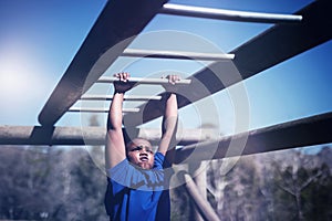 Determined boy exercising on monkey bar during obstacle course