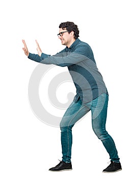 Determined businessman makes effort pushing an heavy invisible object isolated on white background. Confident person, difficult