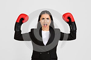 Determined businesswoman with boxing gloves ready to fight