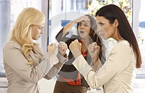 Determined businesswomen fighting at workplace