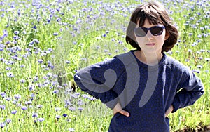 Determined child with sunglasses over sunny blooming floral background