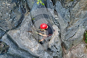 Determined climber clambering up steep wall of rocky mountain. Sportsman overcoming difficult route. Engaging in extreme
