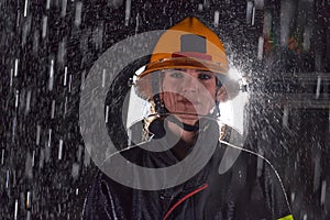 A determined female firefighter in a professional uniform striding through the dangerous, rainy night on a daring rescue
