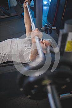 Determined fit man lifting weights, lying on a bench