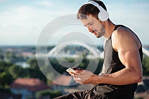 Determined fit young man using a smart phone, listening to music after a workout