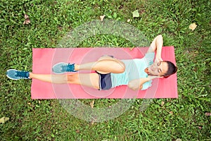 Determined fit young woman doing sit-ups in a park
