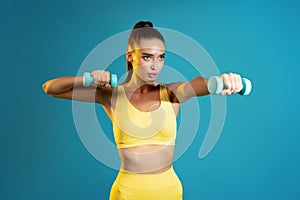 Determined Fitness Woman Exercising With Dumbbells Having Workout, Blue Background