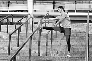 determined male athlete stretching legs outdoor preparing for workout. Warm up firstly. Keeping those muscles flexible photo