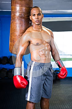 Determined male boxer standing by punching bag