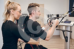 Determined man doing ems training with his coach