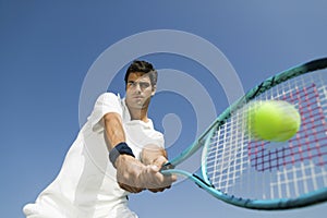 Determined Man Playing Tennis Against Sky