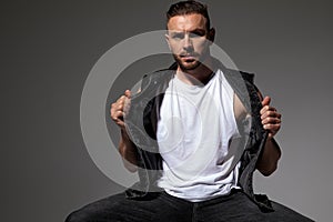 Determined man pulling his jeans jacket and sitting