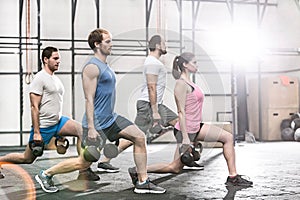 Determined people lifting kettlebells at crossfit gym
