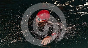 A determined professional triathlete undergoes rigorous night time training in cold waters, showcasing dedication and