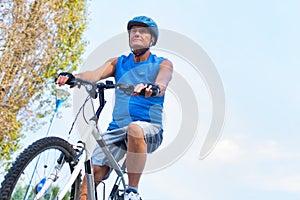 Determined senior man riding bicycle in park