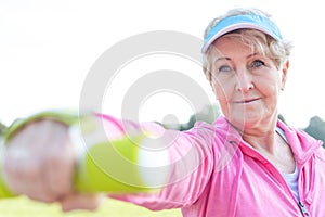 Determined senior woman exercising with dumbbell in park