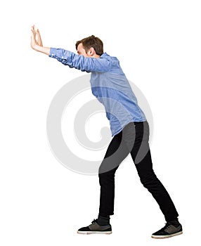 Determined teenage guy making effort as pushing an heavy invisible object isolated on white background. Confident boy, difficult