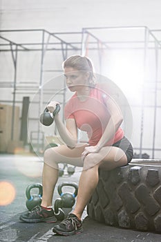 Determined woman lifting kettlebell in crossfit gym