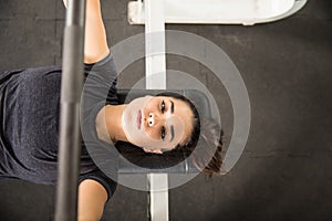 Determined Woman Pumping Muscles With Barbell On Bench Press