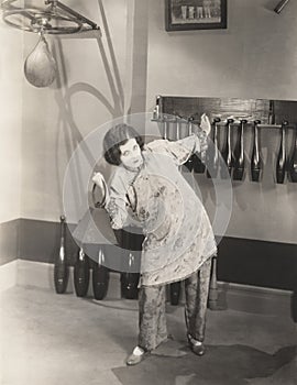 Determined woman in silk pajamas lifting weights in gym