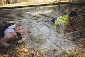 Determined women crawling under the net during obstacle course