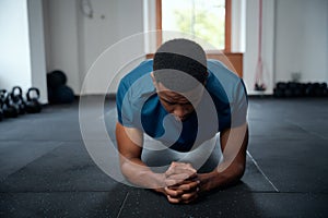Determined young black man in sportswear doing plank exercises at the gym