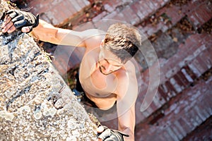 Determined young man climbing a wall while free running