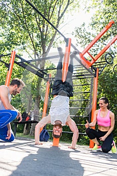 Determined young man practicing handstand motivated by his friends