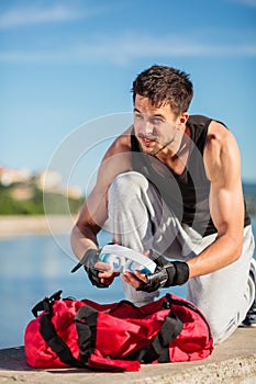 Determined young man pulling headphones out of his gym bag before the workout