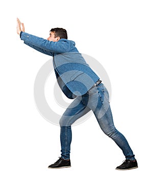 Determined young manmaking effort as pushing an heavy invisible object isolated on white background. Confident guy, difficult task