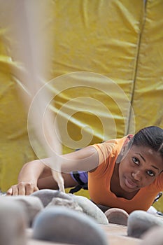 Determined young woman climbing up a climbing wall in an indoor climbing gym, directly above