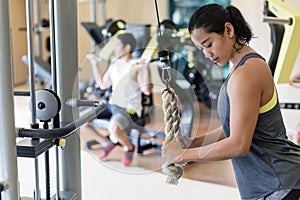 Determined young woman exercising cable rope triceps extension