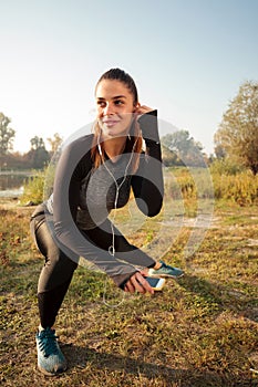 Determined young woman exercising by the river in the early morning