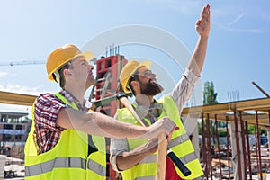 Determined young worker pointing up while imagining the height of a building