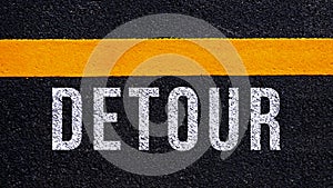 Detour written and yellow line on the road in middle of the asphalt road