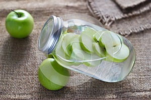 Detox diet fresh green apples soak in water of the jar on sack