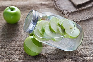 Detox diet fresh green apples soak in water of the jar on sack photo