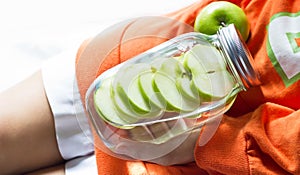 Detox diet fresh green apples soak in water of the jar in woman hand