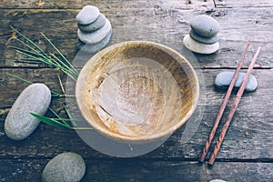 Detox food concept: an empty wooden bowl, wooden chopsticks, bamboo, stones on an old wooden table.