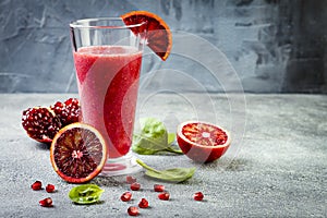 Detox fresh juice or smoothie in glass with blood oranges, greens, pomegranate. Homemade refreshing fruit beverage. Copy space.