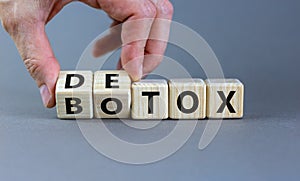 Detox vs botox. Hand turns cubes and changes the word `botox` to `detox` or vice versa. Beautiful grey background. Medical and