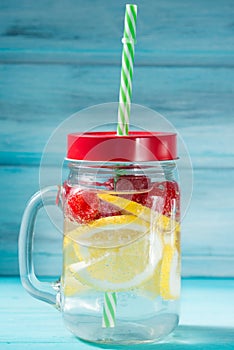 Detox water cocktail with lemon, raspberry and mint, blue wooden background