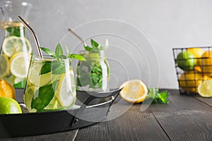 Detox water or lemonade with lemon mint, citrics in glass on wooden table and grey backdrop