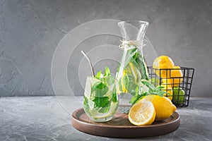 Detox water or lemonade with lemon mint, citrics in glass on wooden table and grey backdrop