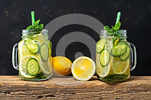 Detox water with sliced lemon and cucumber in a jar on dark background. Healthy concept