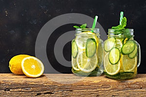 Detox water with sliced lemon and cucumber in a jar on dark background. Healthy concept