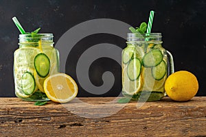 Detox water with sliced lemon and cucumber in a jar on dark background. Healthy concept